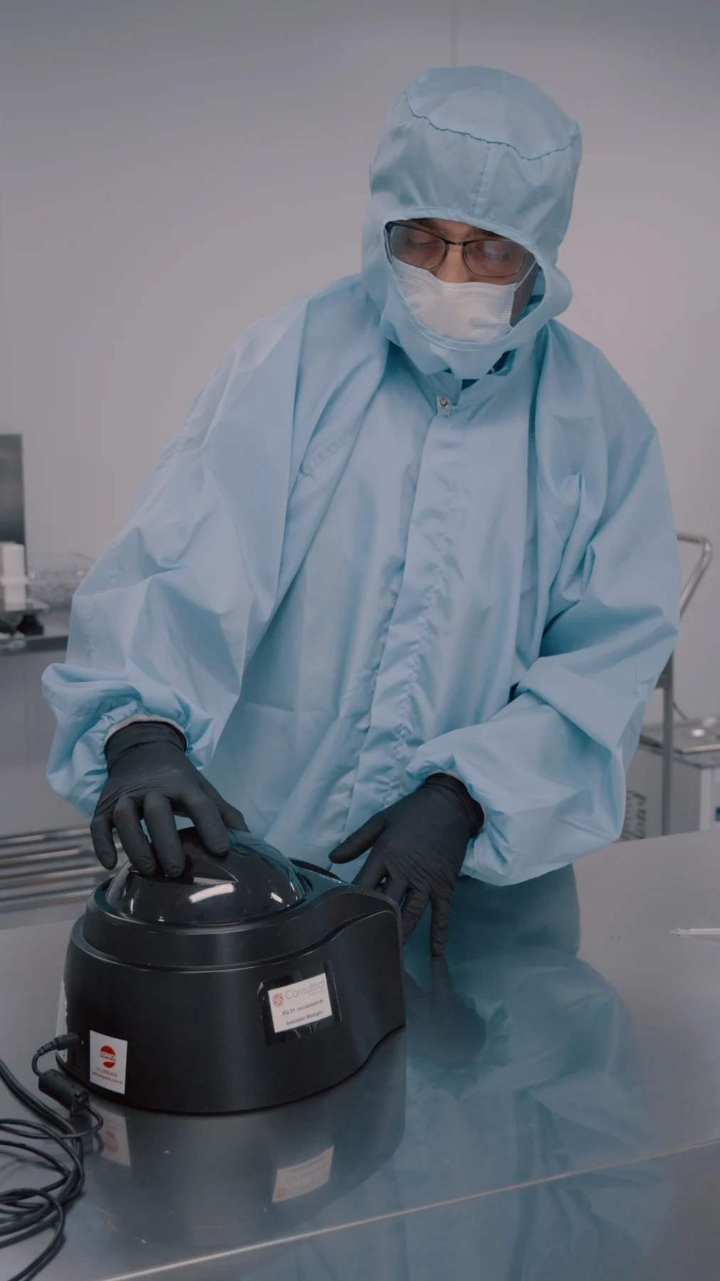 Profissional em ambiente controlado operando equipamento de laboratório